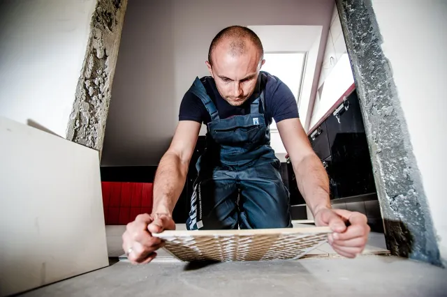 Glazurnik przycina płytkę ceramiczną na budowie podczas prac wykończeniowych