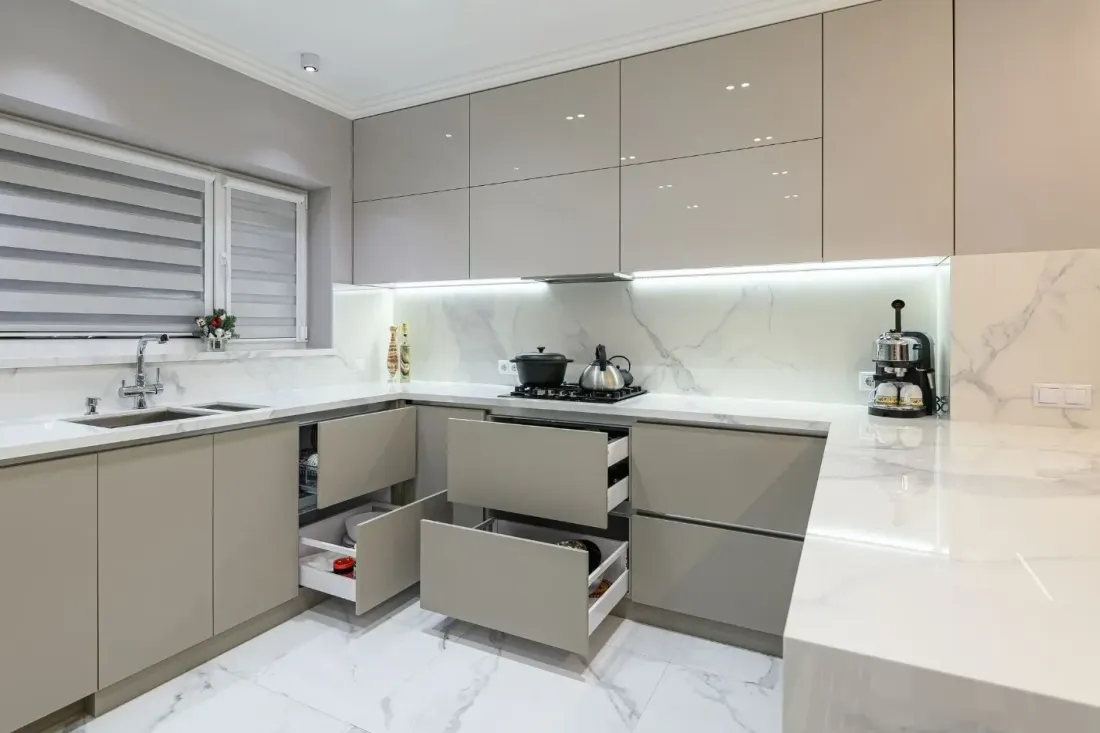 Beżowa kuchnia w kształcie litery U z białym marmurowym blatem i szufladami