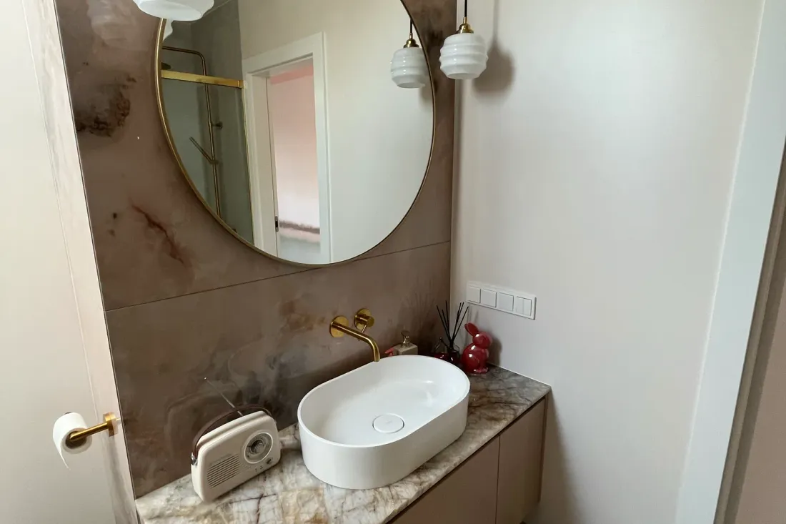 Szeroki blat z umywalką nablatową i ściana z różowego marmuru w łazience