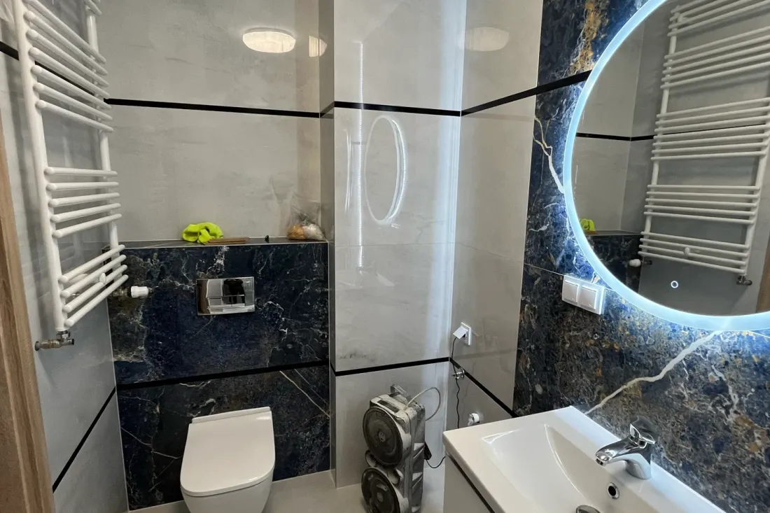 WC podwieszane, granatowa glazura i grzejnik drabinkowy w łazience po remoncie