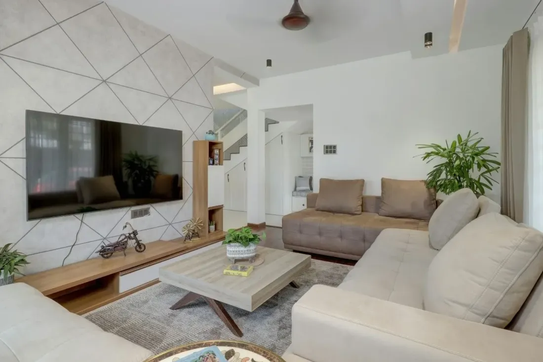 Jasny salon z geometryczną ścianą telewizyjną, dwiema kanapami i drewnianą szafką